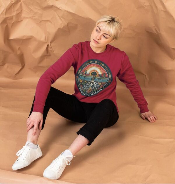 woman wearing "Roots to Riches" organic cotton sweatshirt in cherry color