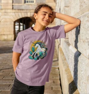 girl wearing mauve shirt with unicorn illustration in prickly pear cactus with sun behind