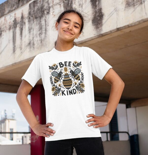 girl wearing white Bee Kind tee with image of bees, flowers, and honey pot in folk art inspired deign