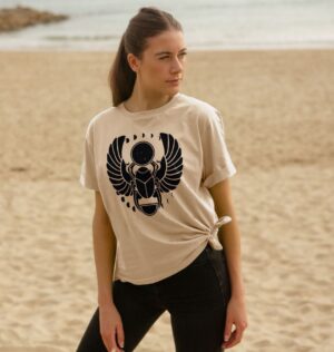 Woman on Beach Wearing the Winged Scarab Organic Cotton Relaxed Tee in Oat Color