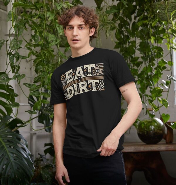 man surrounded by houseplants wearing the Eat Dirt Organic Cotton T-Shirt in Black