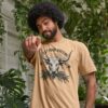 Man wearing the Men's Eat Your Greens Organic Cotton T-Shirt in Sand Color showcasing a steer eating greens