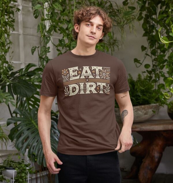 man surrounded by houseplants wearing the Eat Dirt Organic Cotton T-Shirt in Chocolate Color