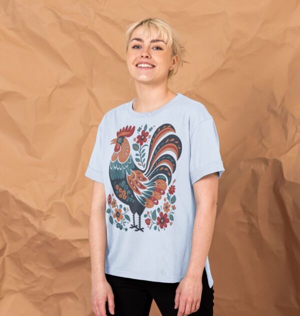 woman wearing the Women's Folk Art Rooster Organic Cotton Relaxed Tee in Sky Blue