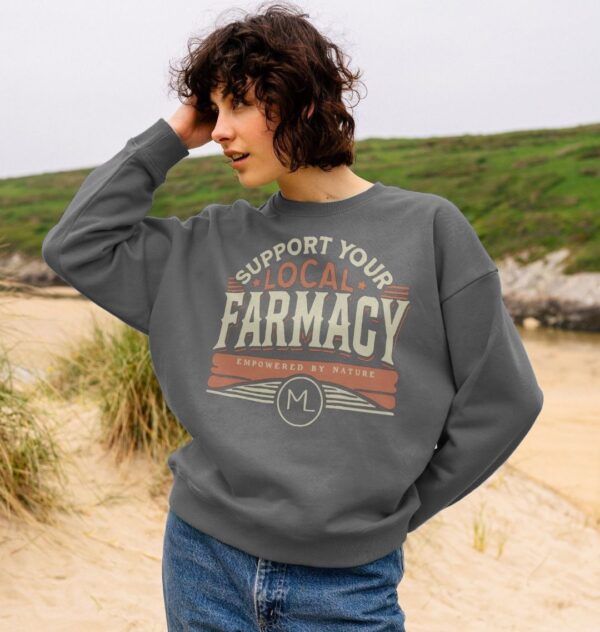 woman on a beach wearing the Women's Support Your Local Farmacy Organic Cotton Sweatshirt in Slate Grey