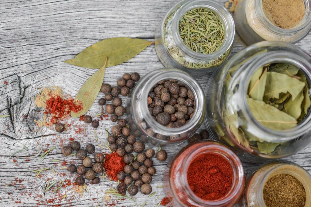 variety of herbs in glass jars on a wooden table