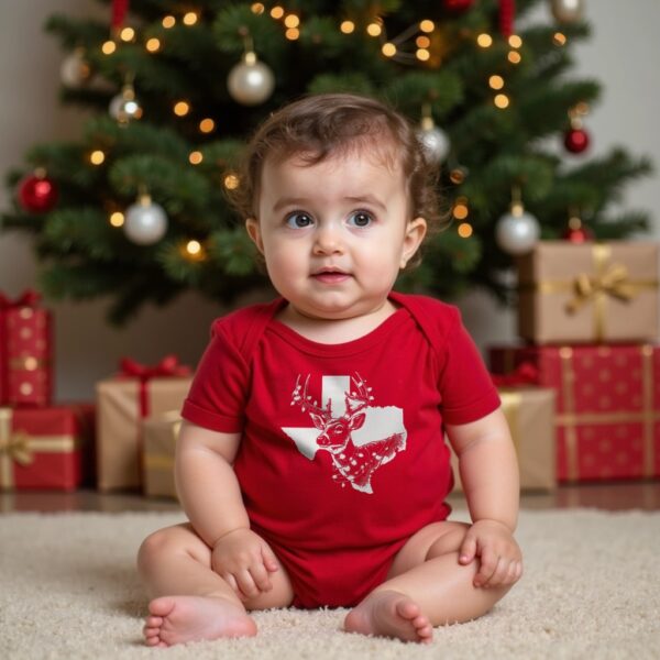 Baby under Christmas tree wearing the red organic cotton Texas Christmas onesie with a white-tailed deer wrapped in lights in front of the shape of Texas.