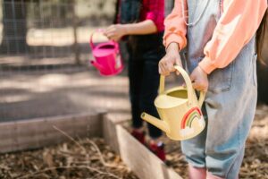 homeschoolers watering a vegetable garden