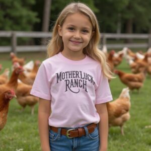 Girl wearing a pink organic cotton t-shirt that says "Mother Luck Ranch" in an old west font. She is standing in front of chickens.