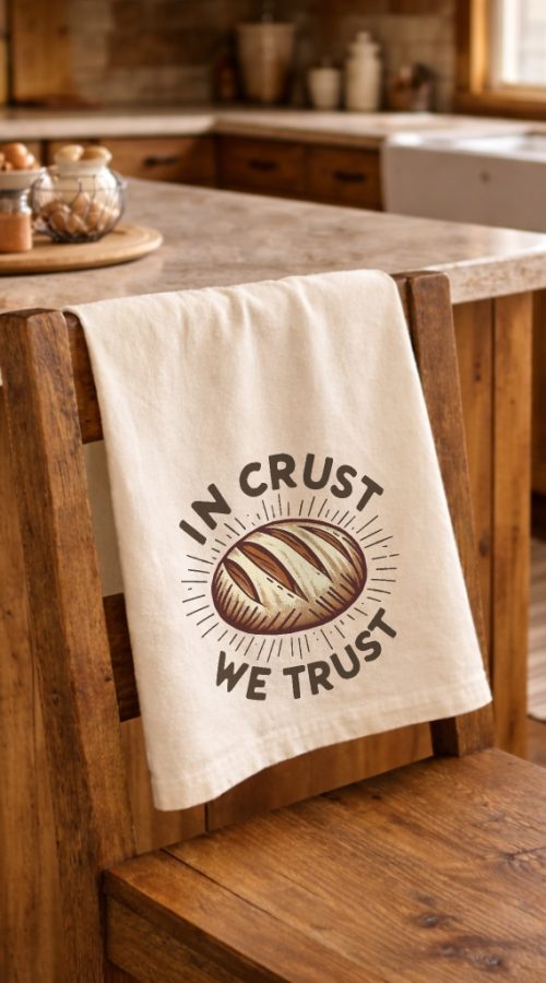 organic cotton dish towel in natural color with In Crust We Trust design hanging over kitchen chair